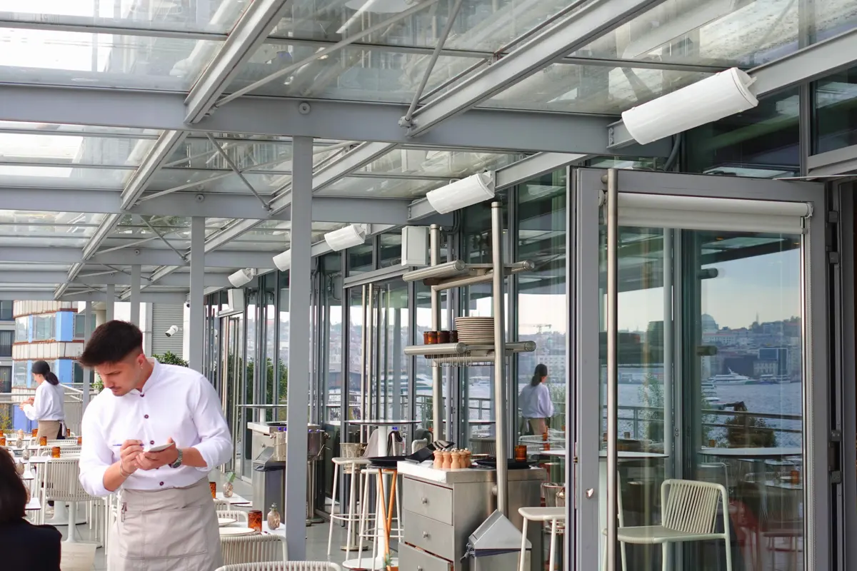 Promienniki HEATSCOPE rozmieszczone wzdłuż strefy stolików na tarasie restauracji