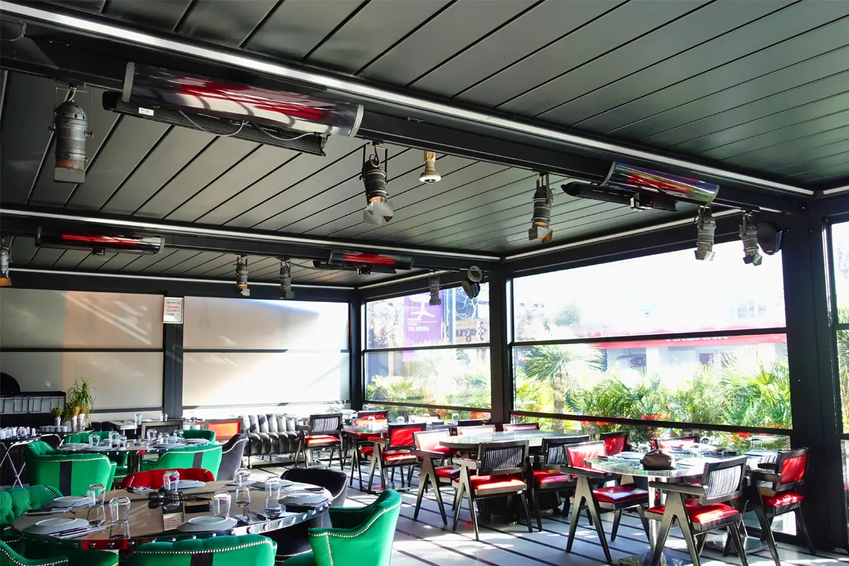 Osłonięty taras restauracji z promiennikami HEATSCOPE rozmieszczonymi nad stolikami